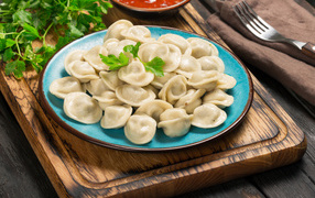 Вкусные пельмени на голубой тарелке 