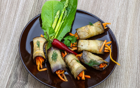 Eggplant rolls with carrots on a plate with lettuce leaves