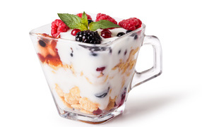 Хлопья с йогуртом и ягодами в стакане на белом фоне