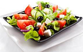 Греческий салат с сыром, помидорами и огурцами на белом фоне