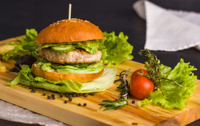 Гамбургер с зеленью на разделочной доске  