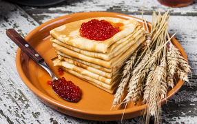 Блины с красной икрой и колосками пшеницы на тарелке