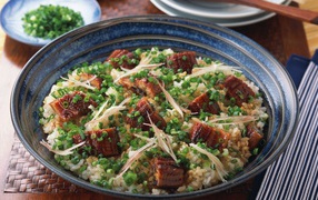 Рисовый плов с кусочками мяса и зеленым луком на столе