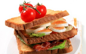 Сэндвич с беконом, яйцами и овощами на белом фоне