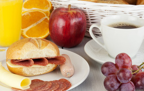 Бутерброд с сыром и колбасой и сок с яблоком и виноградом на завтрак