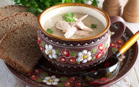 Суп с курицей в красивой тарелке на столе с черным хлебом