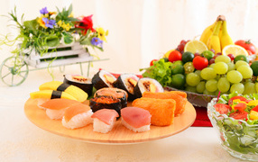 Суши на столе с фруктами и салатом из овощей