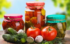 Three jars with preparations from cucumbers, tomatoes and sweet pepper