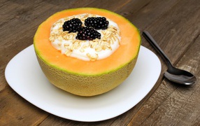 Йогурт с ежевикой и овсянкой в тарелке из свежей дыни на завтрак