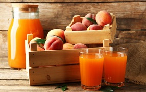 Свежие персики в деревянном ящике со свежим соком на столе