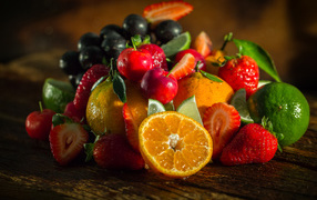 Свежие кусочки апельсина, лимона и ягоды вишни и клубники на столе