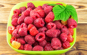 Fresh raspberries in a green bowl on a table