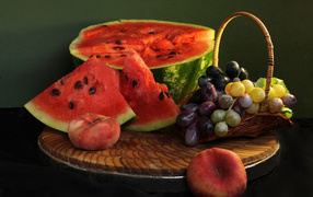 Нарезанный арбуз на столе с виноградом и персиками