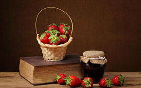 Strawberry jam, fresh strawberries and a book on the table