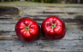 Два больших красных яблока на деревянном столе