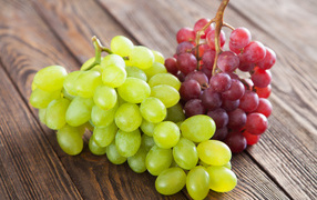 Two clusters of white and pink grapes on a table