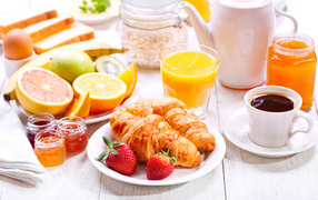 Croissants with strawberries, honey and citrus for breakfast