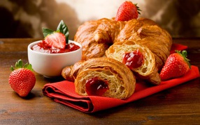 Fresh croissants with strawberry jam and strawberries on the table