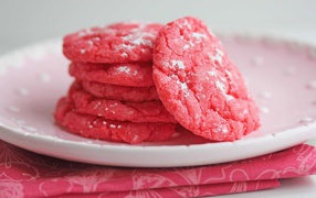 Pink cookies on a white plate with powdered sugar