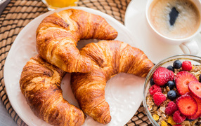 Three fresh croissants and muesli with berries for breakfast