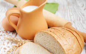 Белый нарезанный батон на столе с молоком