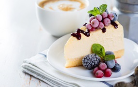 A piece of cheesecake with frozen berries and a cup of coffee on the table
