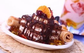 Аппетитное пирожное с шоколадной глазурью, трубочками и мандаринами