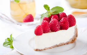 Appetizing piece of cheesecake with fresh raspberries and mint leaves