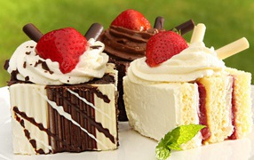 Appetizing pieces of cake with cream, chocolate and strawberries