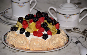 Торт с безе и свежими ягодами на столе 