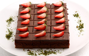 Шоколадное пирожное со свежей клубникой на белой тарелке