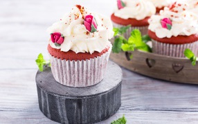 Шоколадный капкейк с кремом и розочками на столе