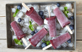 Вкусное черничное мороженое на палочке в лотке со льдом