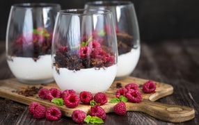 Dessert with cream, chocolate and fresh raspberries in glass glasses