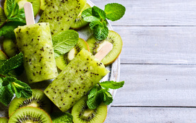 Мороженое с киви и листиками мяты на деревянном столе