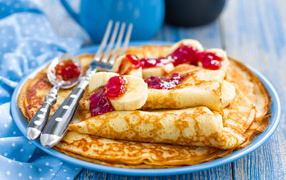 Блины с клубничным джемом и бананами на блюде 