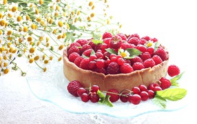 Пирог с ягодами малины и смородины на столе с ромашками