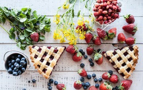 Кусочки пирога на столе с ягодами клубники и черники