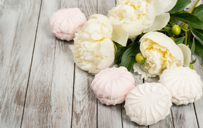 Сладкий зефир на столе с белыми пионами