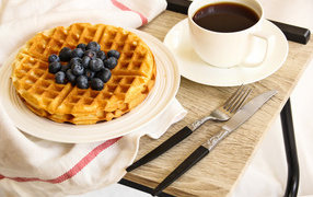 Сладкие вафли с черникой и чашкой кофе на завтрак