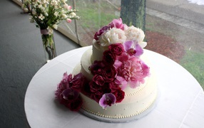 Большой свадебный торт украшен живыми цветами
