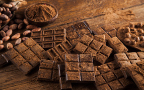 Плитки черного шоколада на столе с какао бобами