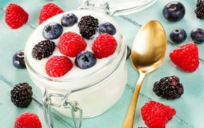 Йогурт со свежими ягодами малины, черники и ежевики в стеклянной банке на завтрак