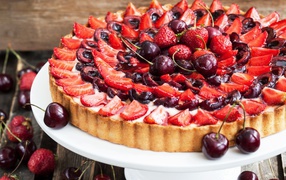Pie with fresh appetizing strawberries and cherries
