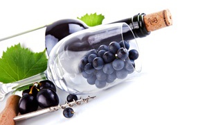 Бутылка вина с бокалом и виноградом на белом фоне