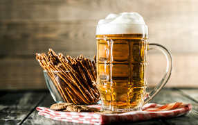 Бокал свежего пива с выпечкой на столе