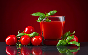 Стакан томатного сока со свежими помидорами на столе