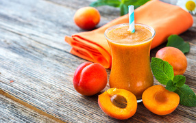 Абрикосовый смузи в стакане на столе со свежими ягодами