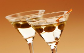 Напиток мартини в бокалах с оливками на кремовом фоне