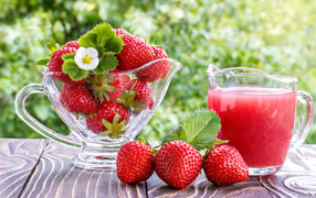 Клубничный сок в стеклянном графине на столе со свежей клубникой